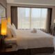 Elegant hotel room with modern decor, large bed, and sunlit window view.