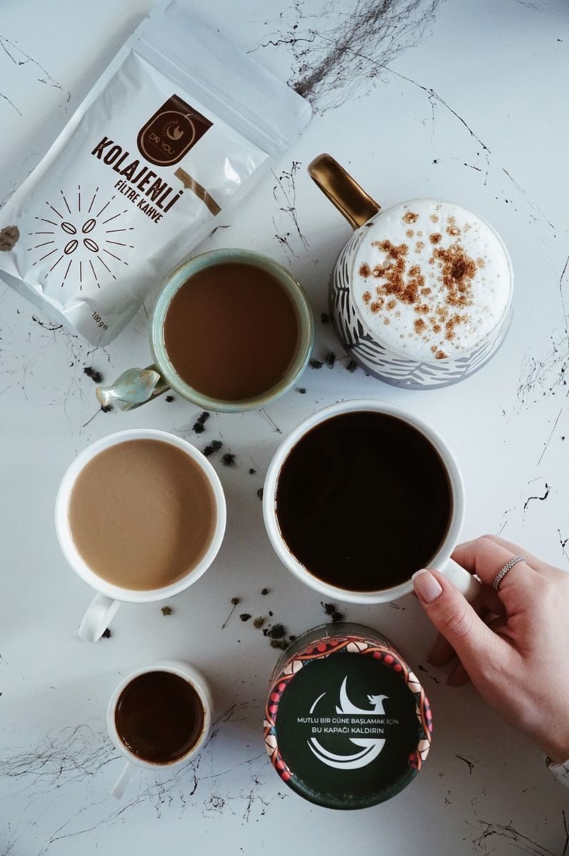 Top view of various coffee drinks and a hand selecting a cup in a cozy İstanbul cafe setting.