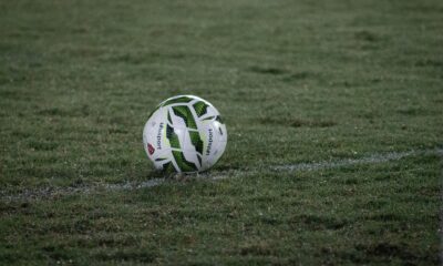 A soccer ball resting on a grass field, captured during nightfall with visible dew.