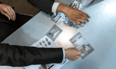 Detectives analyzing black and white photos and fingerprints. Investigation process depicted in detailed top view.