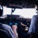 Back view of anonymous male pilots in uniform and headset navigating modern airplane while taking off