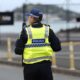 Back view of a police officer walking along a city street, ensuring safety.