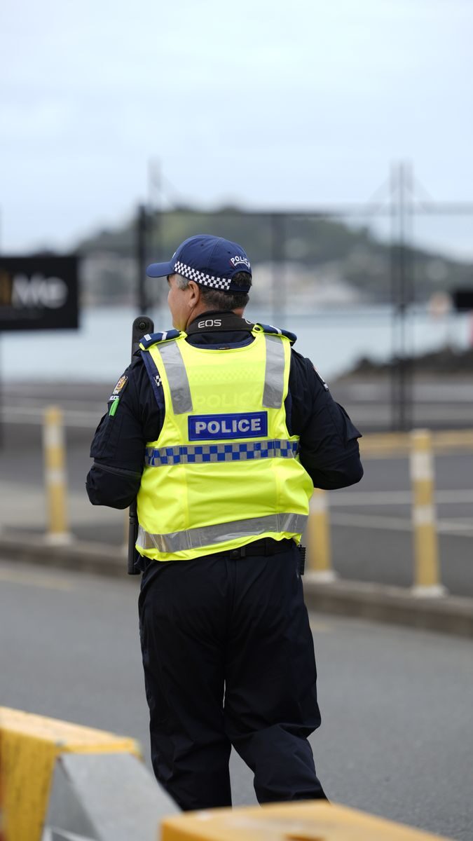 Back view of a police officer walking along a city street, ensuring safety.