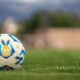 A detailed photo of a soccer ball on a lush grass field with blurred background.