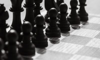 Black and white photo of chess pieces arranged on a chessboard, capturing strategic anticipation.