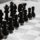 Black and white photo of chess pieces arranged on a chessboard, capturing strategic anticipation.