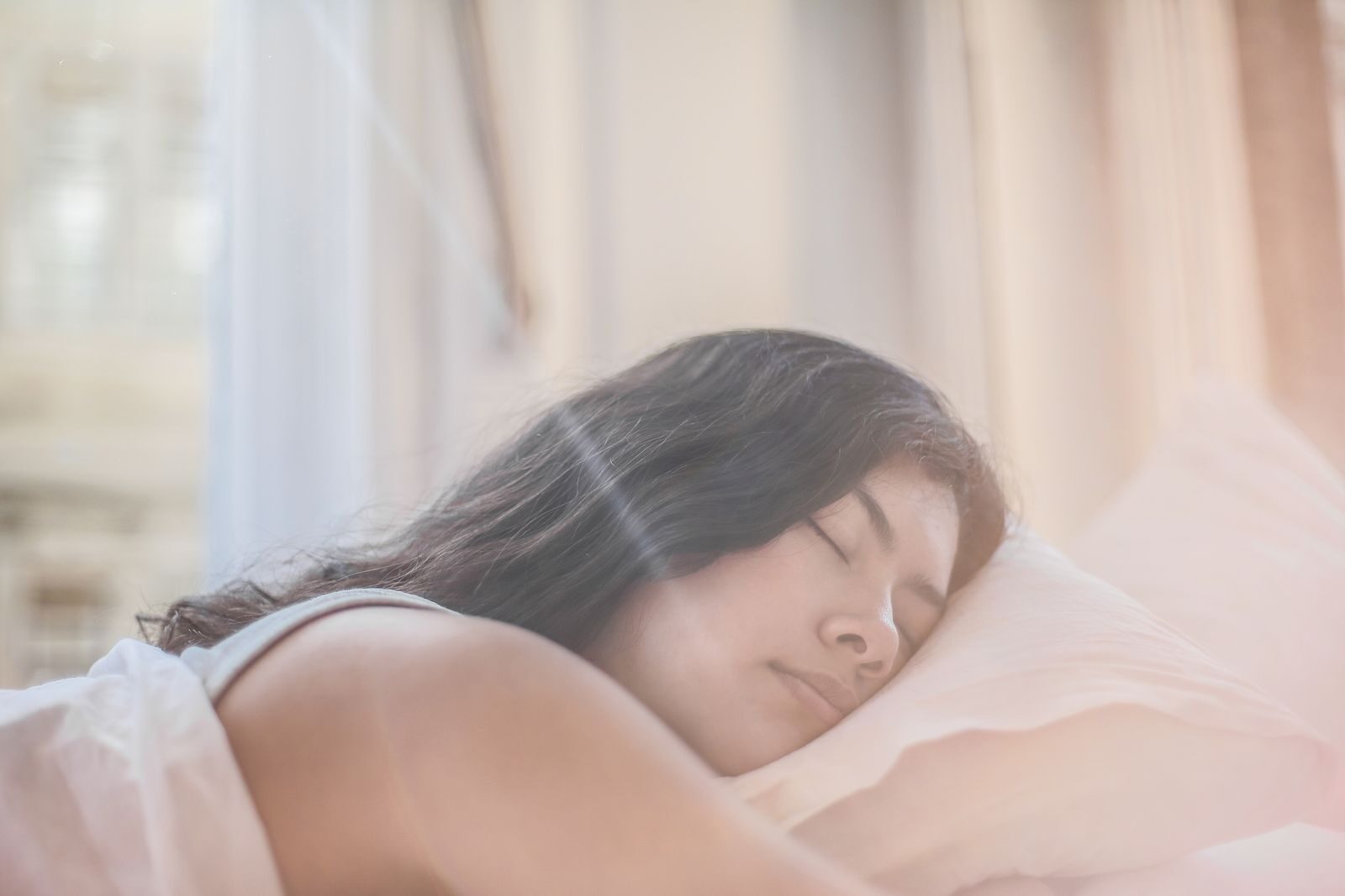 Portrait of a woman sleeping peacefully in soft morning light indoors.