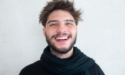 Cheerful young man with a beard smiling warmly, wearing a scarf.