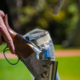 Detailed view of a shotgun ejecting spent shells during target practice in a grassy outdoor area.
