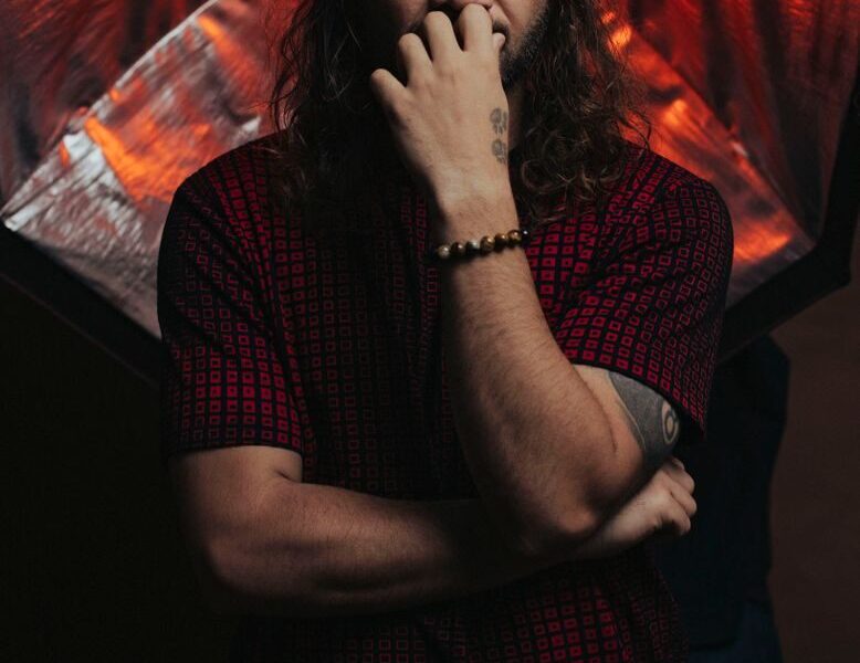 A pensive man poses with studio lights creating a striking, dramatic effect.