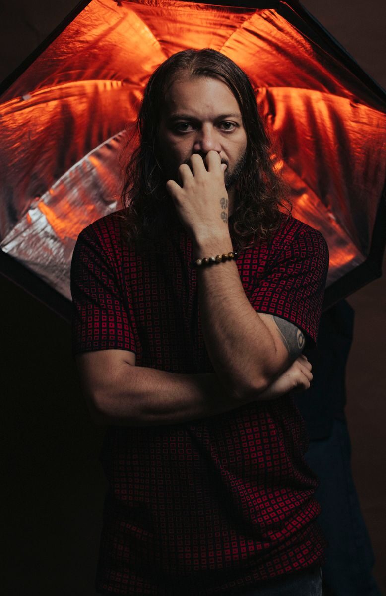 A pensive man poses with studio lights creating a striking, dramatic effect.