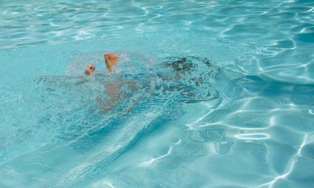 A man swimming in a pool with no shirt on