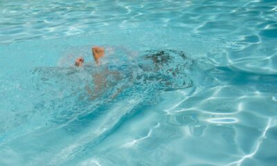 A man swimming in a pool with no shirt on