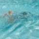 A man swimming in a pool with no shirt on