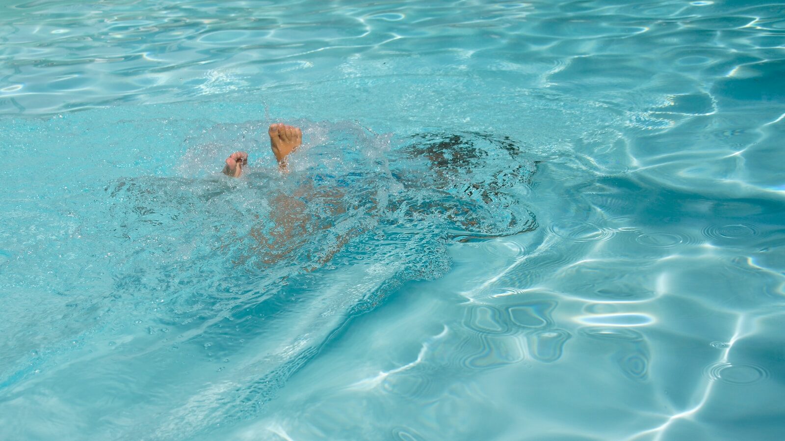 A man swimming in a pool with no shirt on