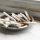 A close-up of an ashtray filled with cigarette butts on a white surface, symbolizing smoking habits.