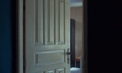 A classic wooden door slightly open, revealing a glimpse into a dimly lit interior space.