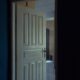 A classic wooden door slightly open, revealing a glimpse into a dimly lit interior space.