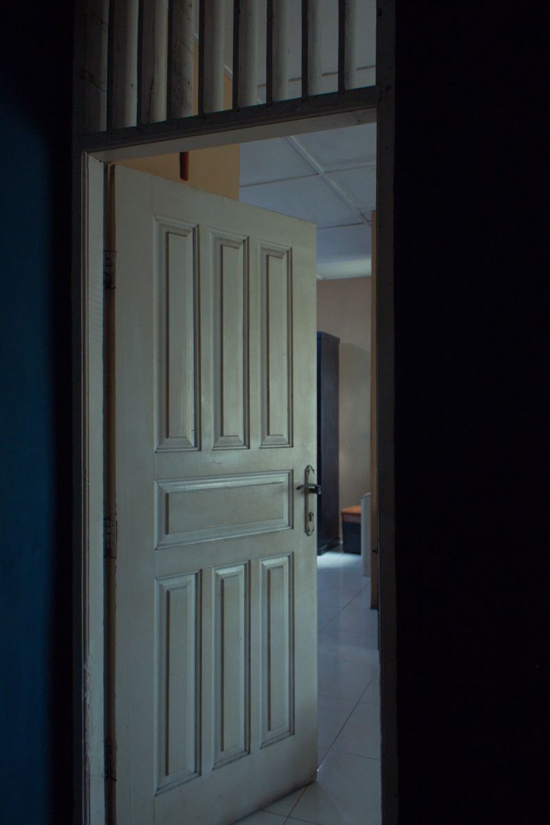 A classic wooden door slightly open, revealing a glimpse into a dimly lit interior space.