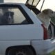 Two dogs rest in the trunk of a car parked in a rural setting, enjoying the fresh air.