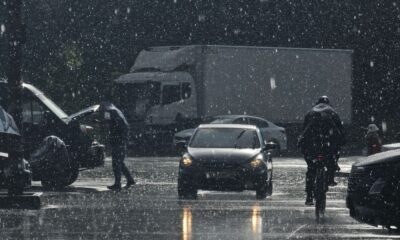Moody urban street scene in heavy rain with cars and pedestrians.