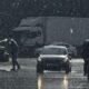 Moody urban street scene in heavy rain with cars and pedestrians.