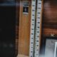 An antique wooden barometer with a classic design, set against a wooden backdrop.