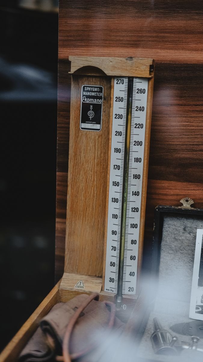 An antique wooden barometer with a classic design, set against a wooden backdrop.