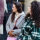 Pensive women friends in casual clothes standing with shopping bags near shop on street in daytime