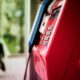 Vibrant red public telephone booth in urban setting with blurred background.