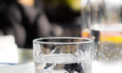 Close-up of a crystal glass filled with water on a sunlit table, perfect for summer refreshment themes.