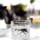 Close-up of a crystal glass filled with water on a sunlit table, perfect for summer refreshment themes.