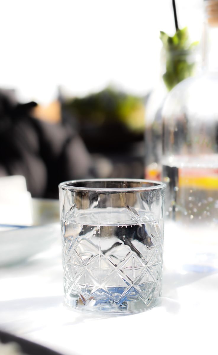 Close-up of a crystal glass filled with water on a sunlit table, perfect for summer refreshment themes.