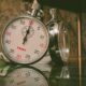 A detailed view of a classic analog stopwatch with reflection on a glass surface.
