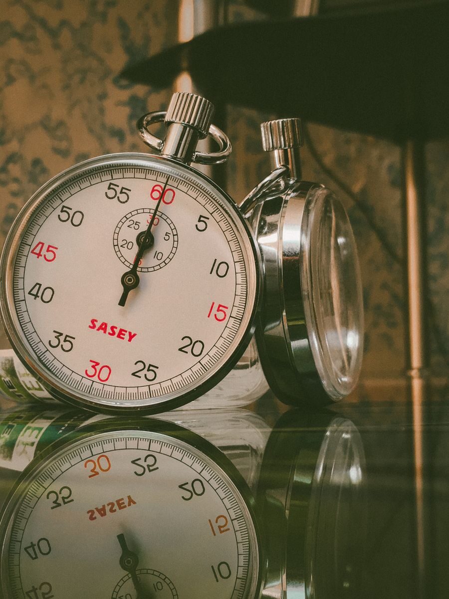 A detailed view of a classic analog stopwatch with reflection on a glass surface.