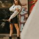 Stylish woman in leather skirt against graffiti wall in urban environment.
