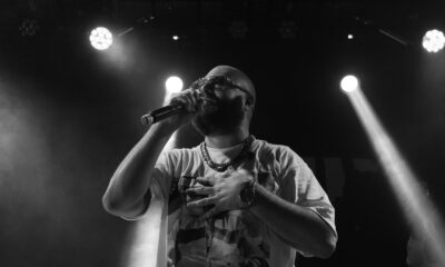 Black and white image of a bearded musician singing live with dynamic lighting.