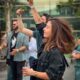 People enjoying a lively outdoor party, dancing and smiling under the day sky.