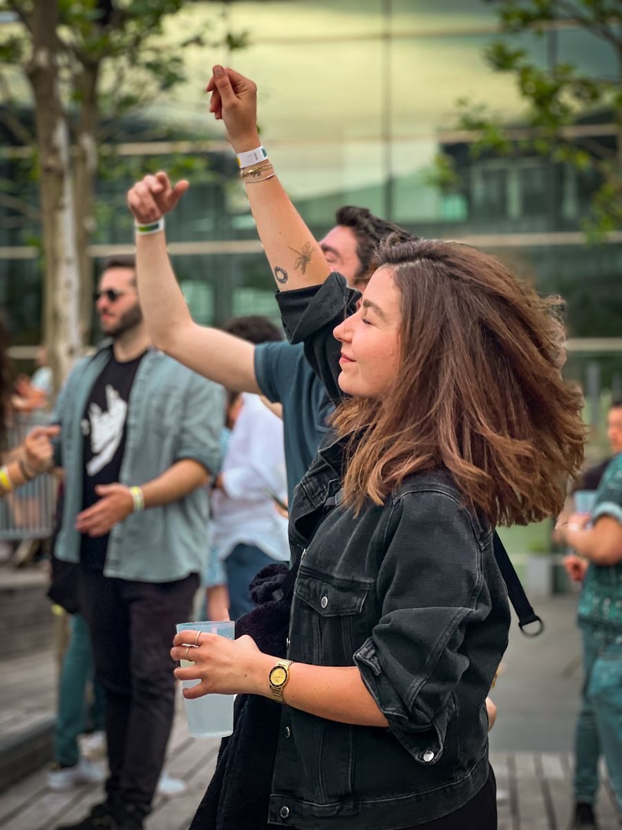People enjoying a lively outdoor party, dancing and smiling under the day sky.