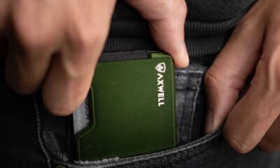 Close-up of a hand holding a minimalist green metal wallet, perfect for everyday carry fashion enthusiasts.