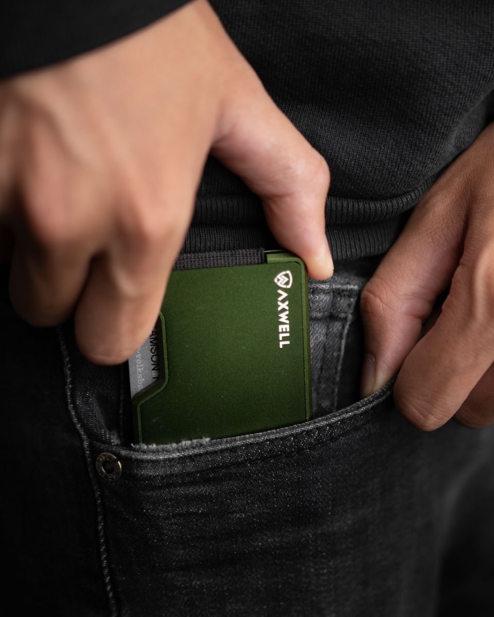 Close-up of a hand holding a minimalist green metal wallet, perfect for everyday carry fashion enthusiasts.