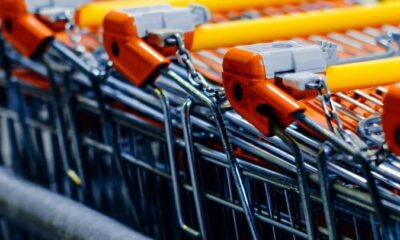 Close-up of orange-handled shopping carts lined up in a store aisle.