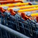 Close-up of orange-handled shopping carts lined up in a store aisle.