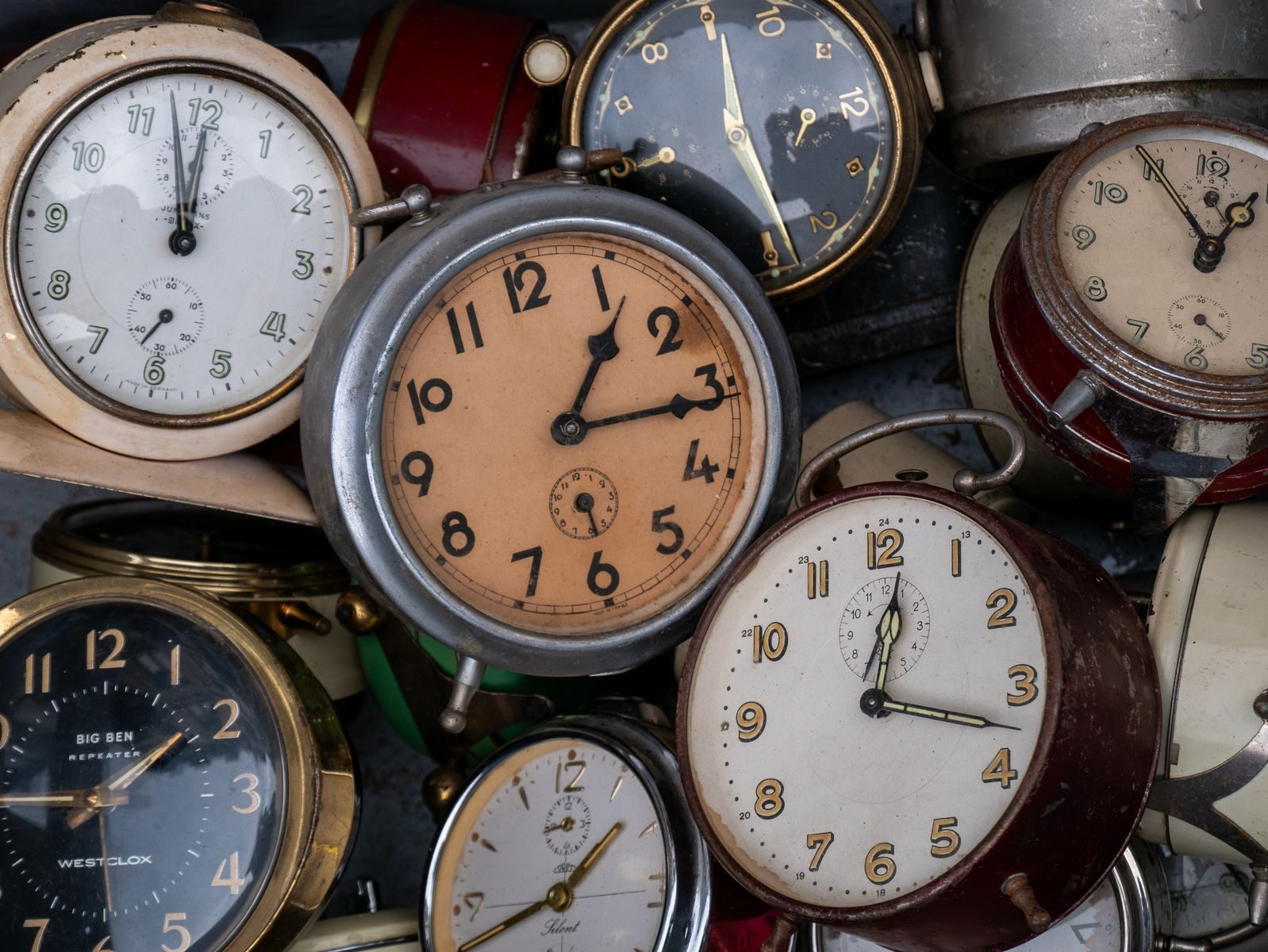 Close-up view of a collection of vintage alarm clocks with various designs, showcasing time's passage.
