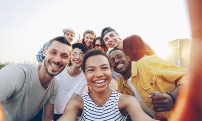 A diverse group of friends taking a joyful selfie outdoors during sunset.