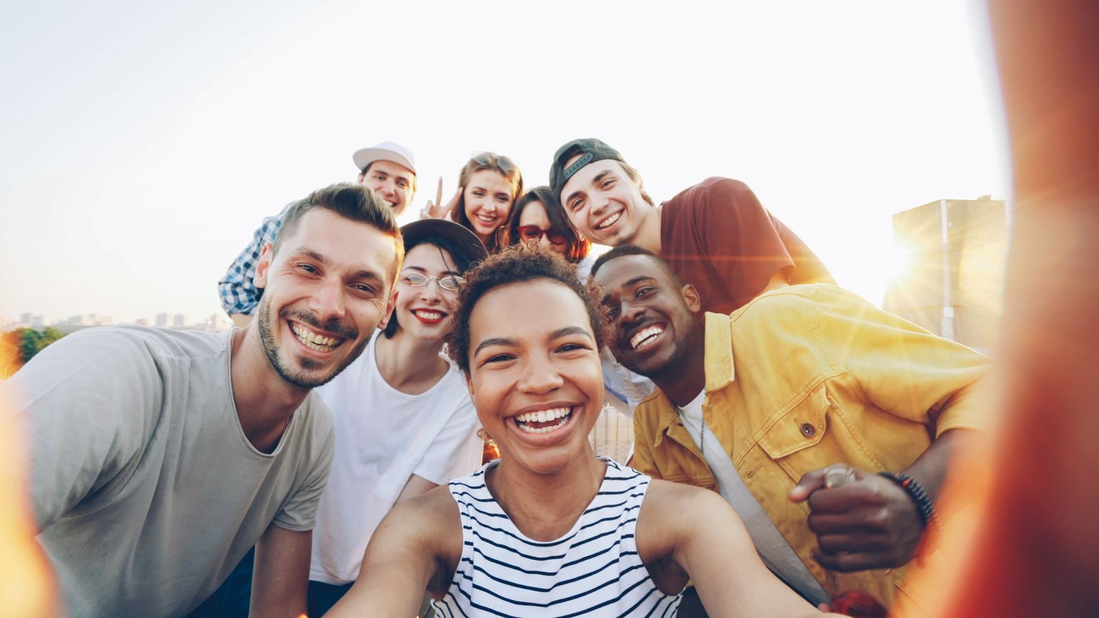 A diverse group of friends taking a joyful selfie outdoors during sunset.