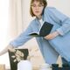 A young woman multitasks with a phone call and notebook in a casual home office setting.