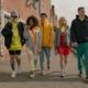 A group of stylish young adults walking together on a city street, showcasing modern fashion.