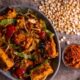 A delicious tofu stir-fry with cherry tomatoes, lettuce, and spices served in a rustic style.