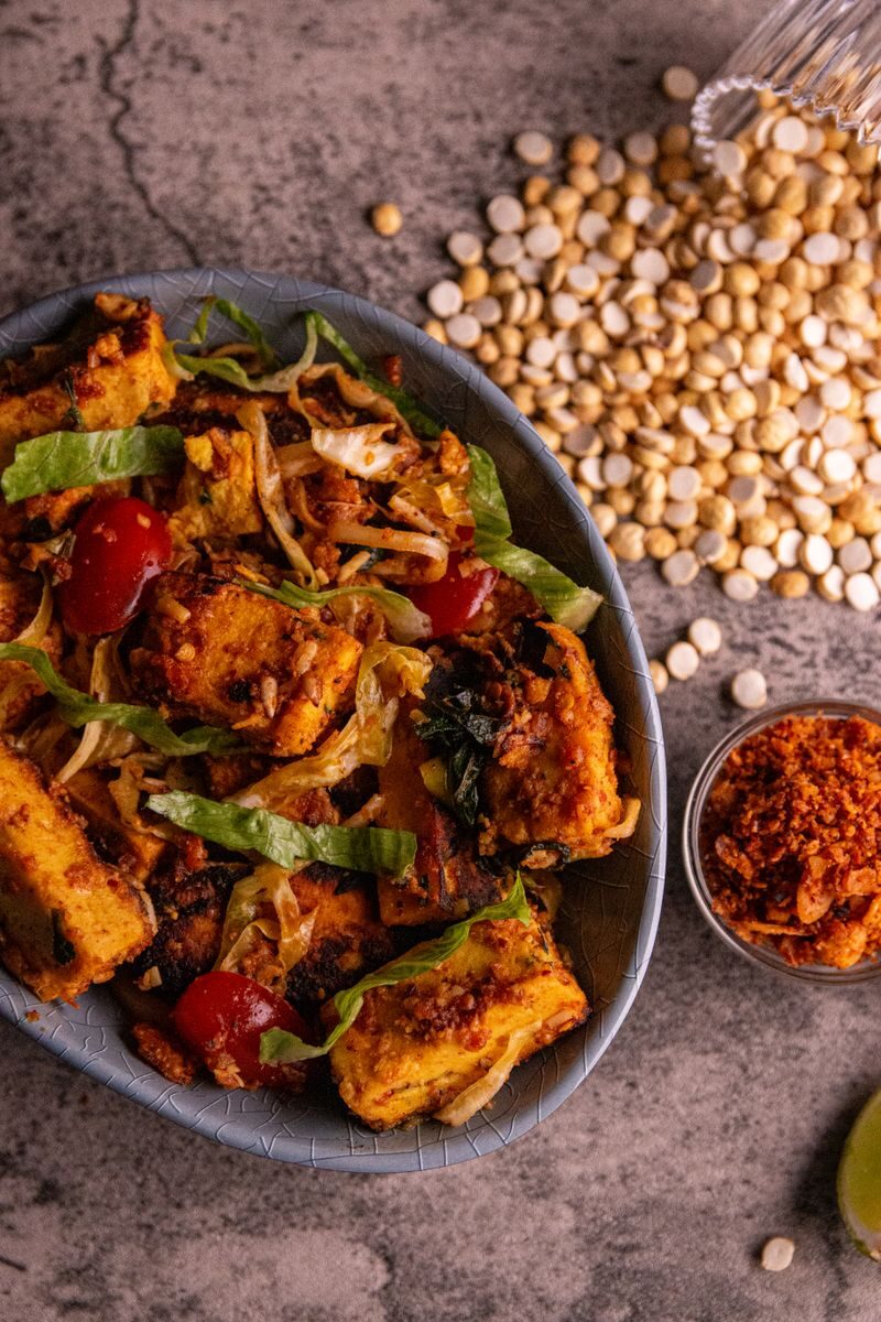 A delicious tofu stir-fry with cherry tomatoes, lettuce, and spices served in a rustic style.